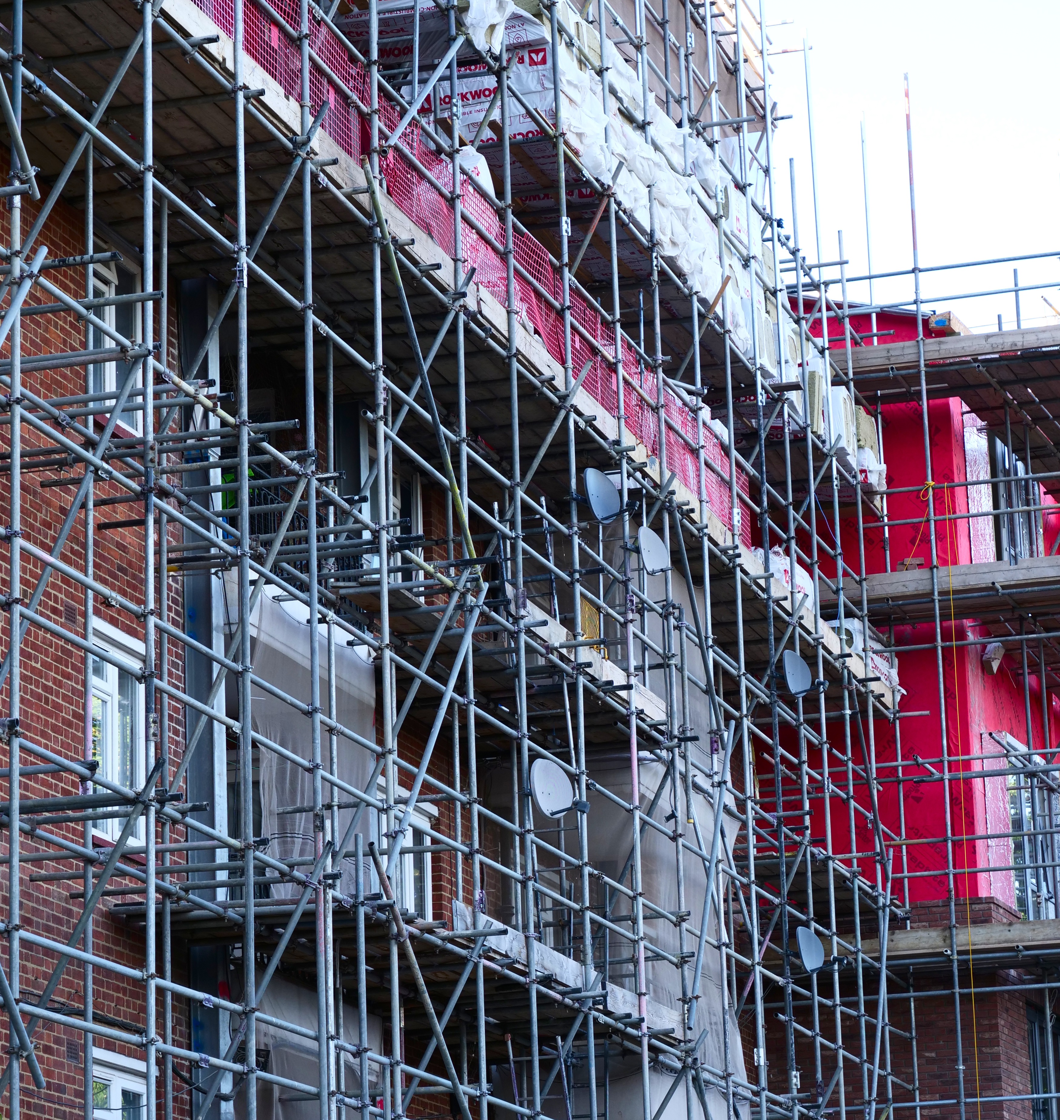 Roderick House covered with scaffolding. There is a large quantity of insulation staged on the scaffolding awaiting installation. There are satellite dishes attached to the scaffolding, which have had to be moved from the wall of the house to accommodate the scaffolding.